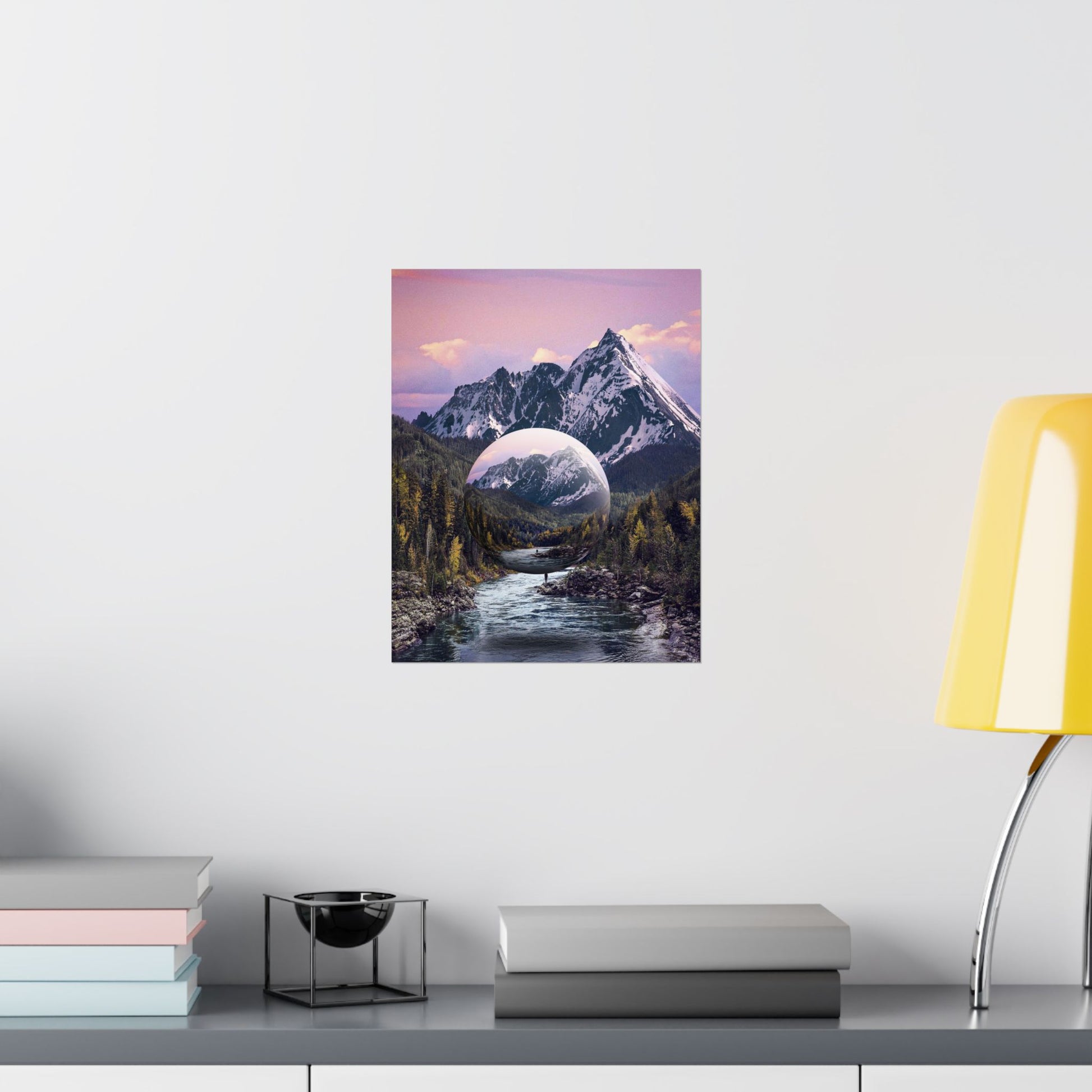 Framed artwork of a mountain landscape with a river on a white wall above a shelf.