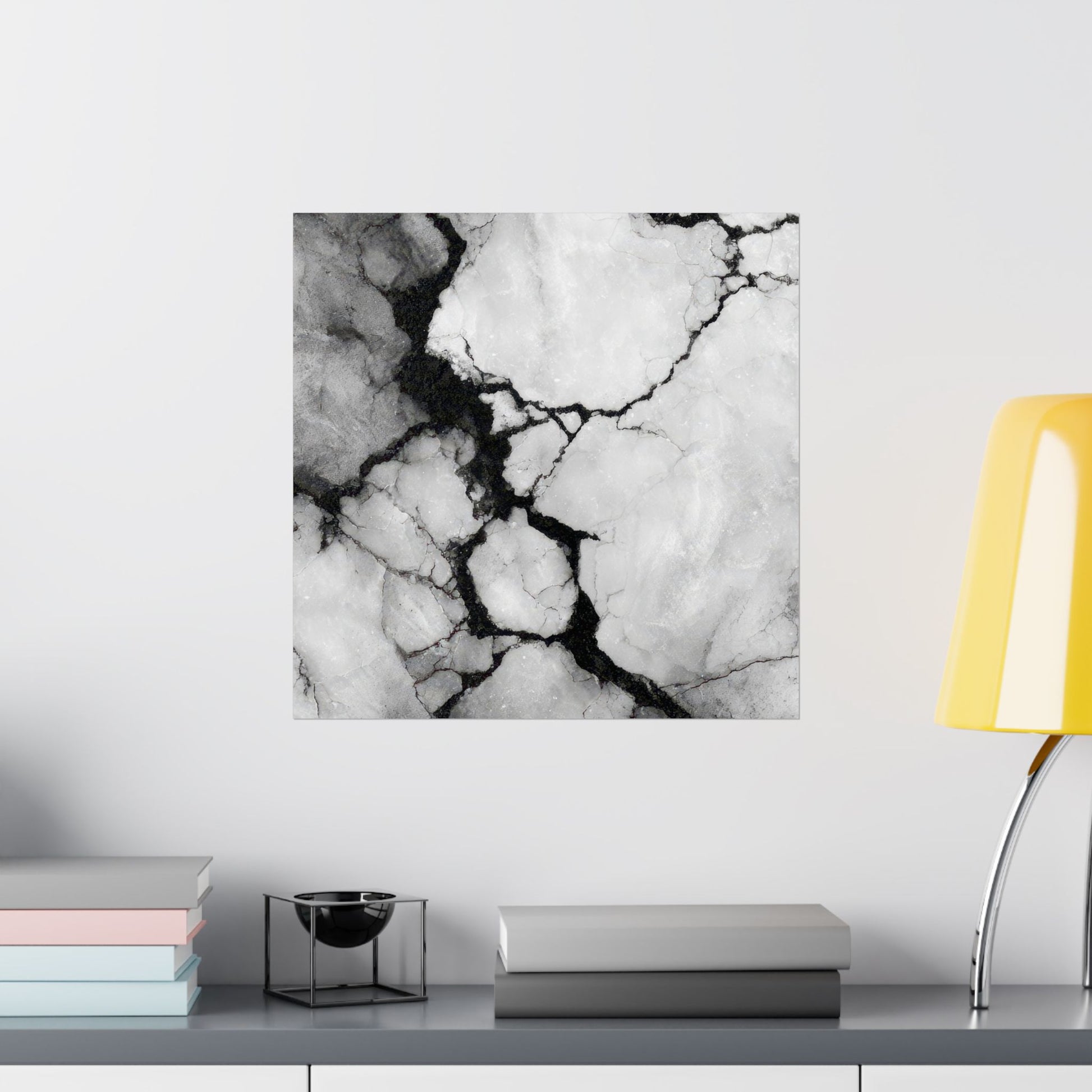 Marble-patterned wall art on a white wall with books and a lamp in the foreground.