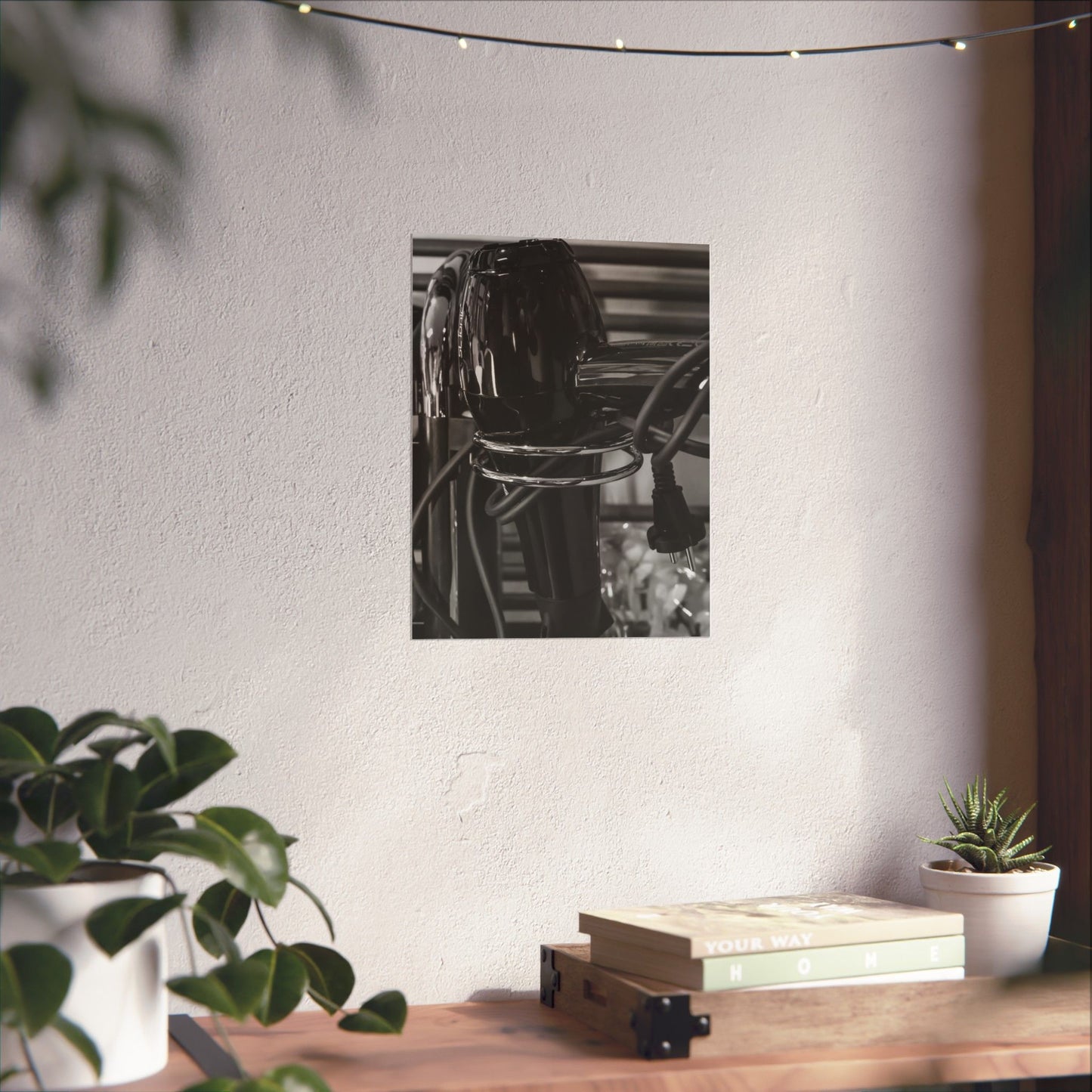 Black and white photo of a bicycle on a wall above a wooden table with plants and books.
