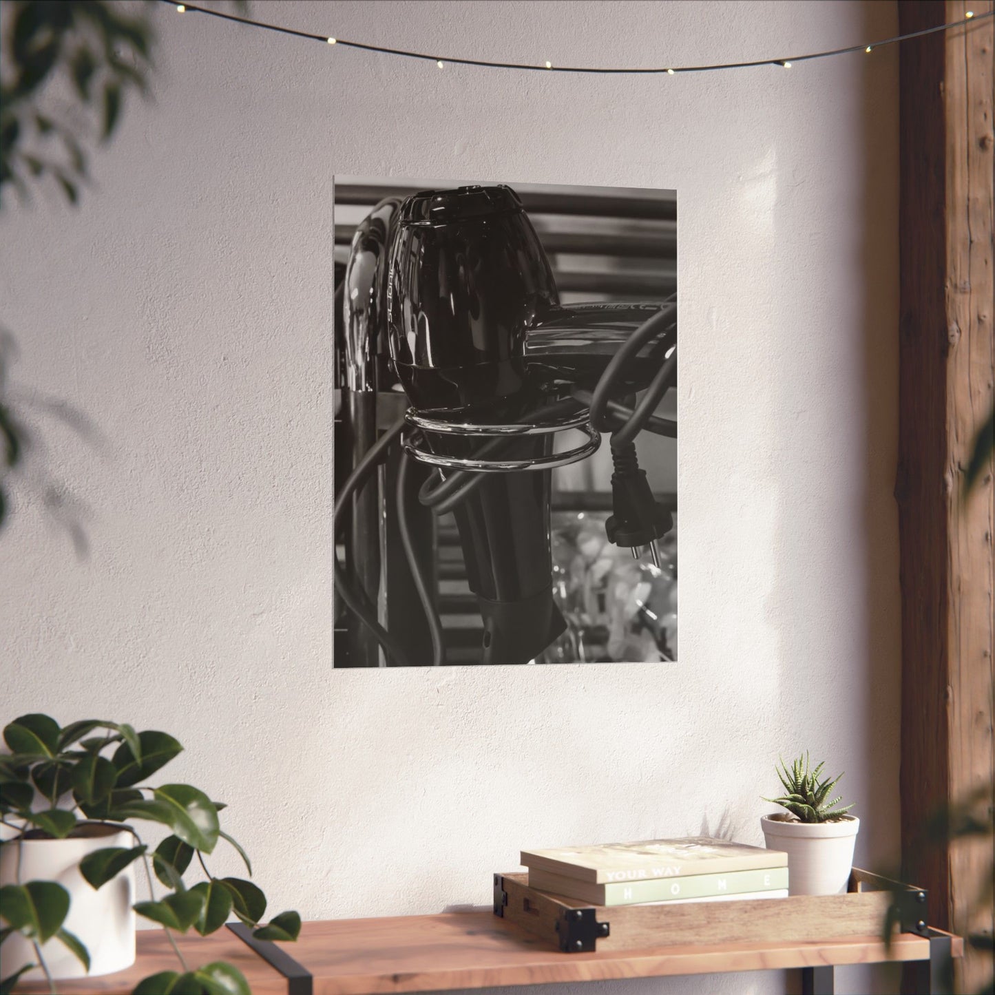 Black and white photo of a chair on a white wall with plants and a wooden table below.
