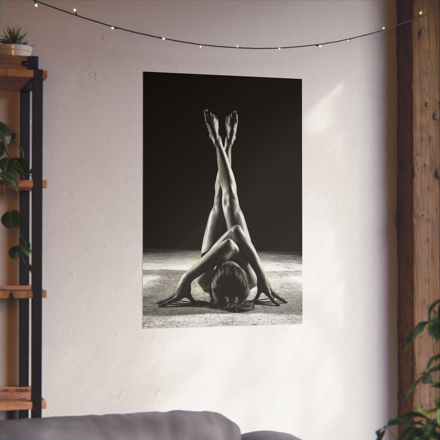 Poster of a person in a yoga pose on a wall in a room with plants and a shelf.