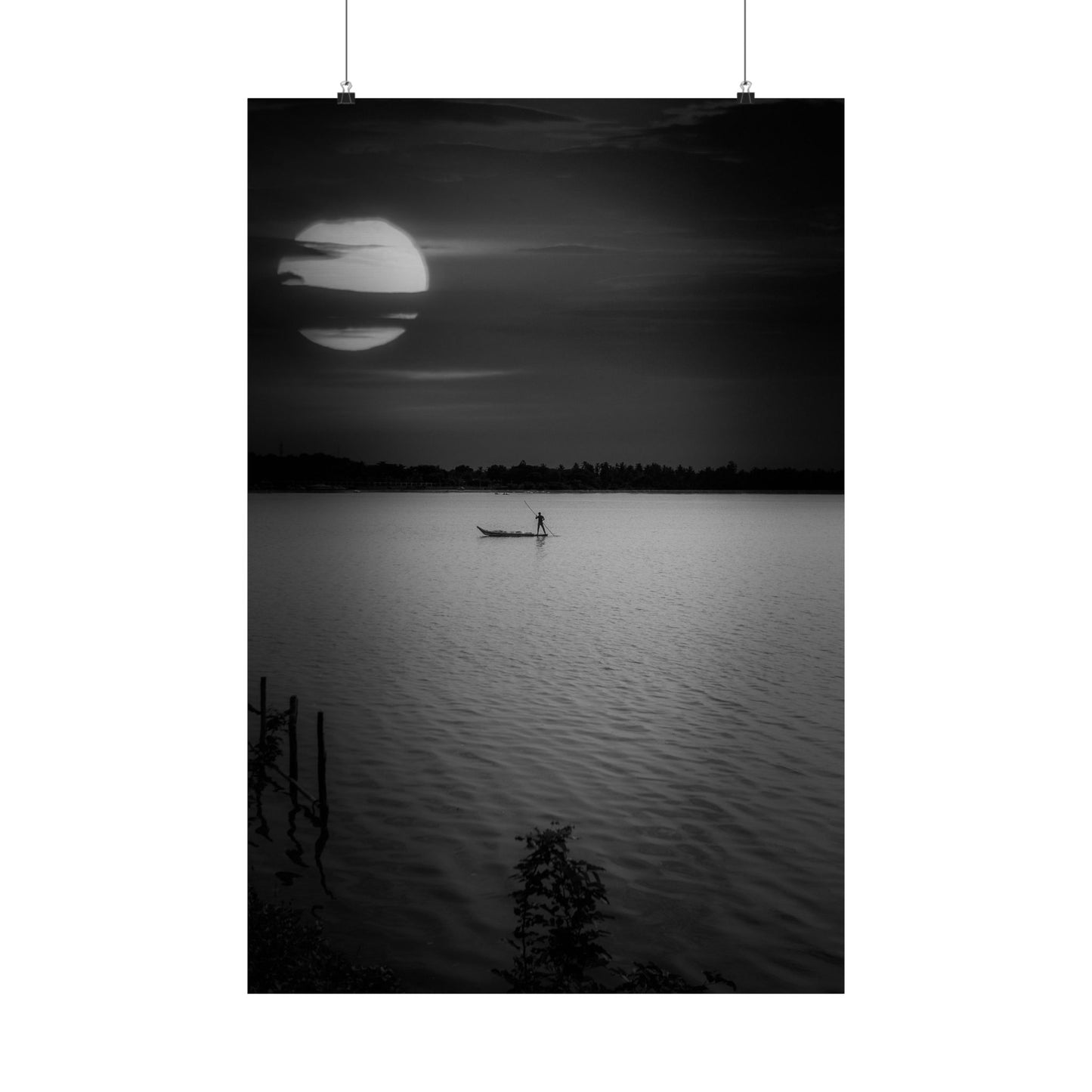 Black and white photo of a person in a boat on a lake with a large moon in the sky.