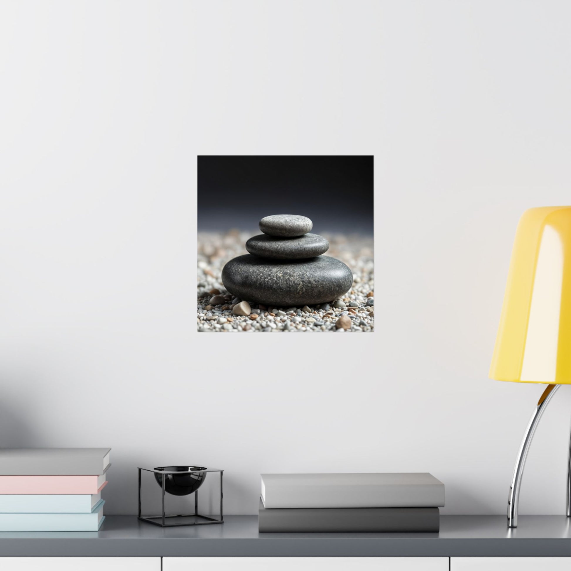 Stack of stones on pebbles with a yellow lamp and books on a shelf in the background