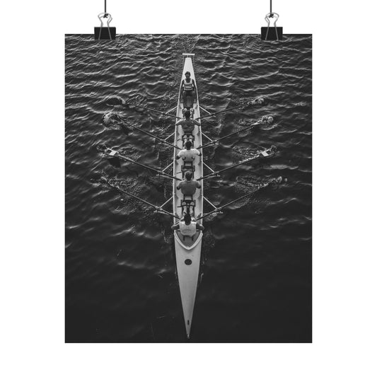 Black and white photo of a rowing boat with rowers on water