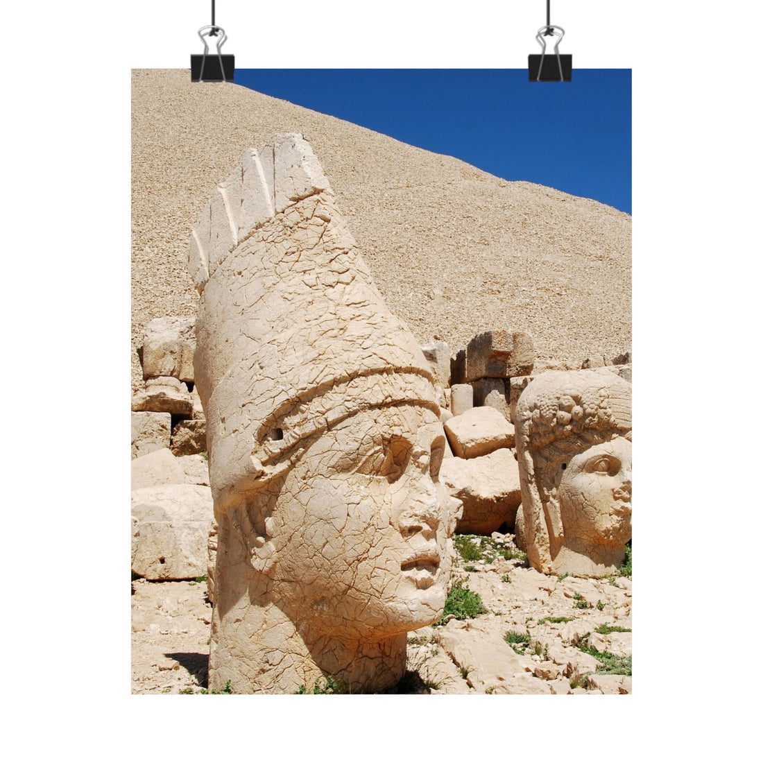 Stone heads of ancient statues on a rocky hillside with blue sky