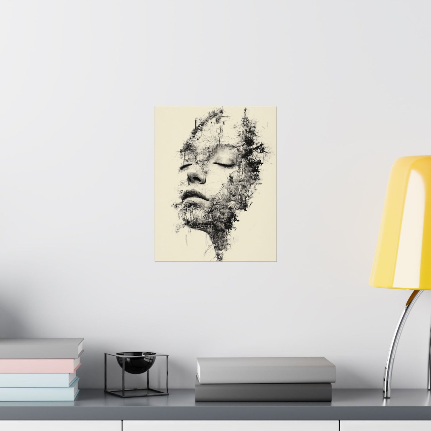 Abstract art print of a face on a wall above a shelf with books and a lamp.