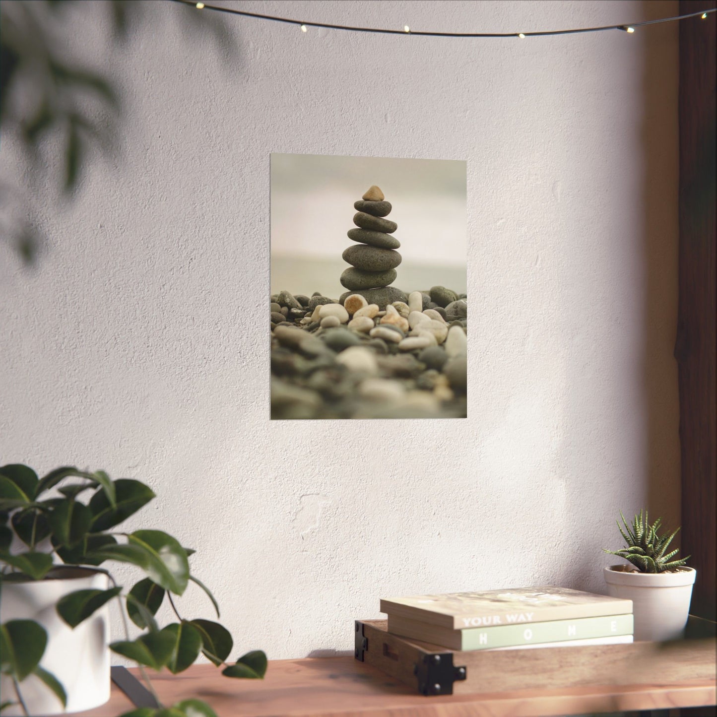 Stylized image of stacked stones on a pebbly surface with a plant and books in the foreground.