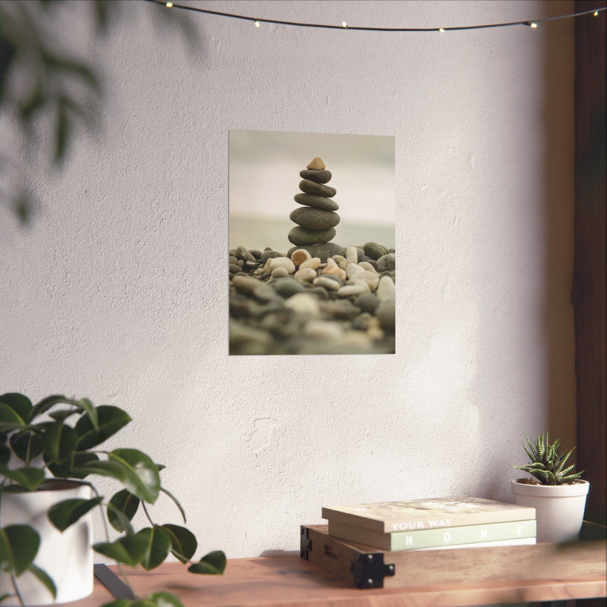 Stylized image of stacked stones on a pebbly surface with a plant and books in the foreground.