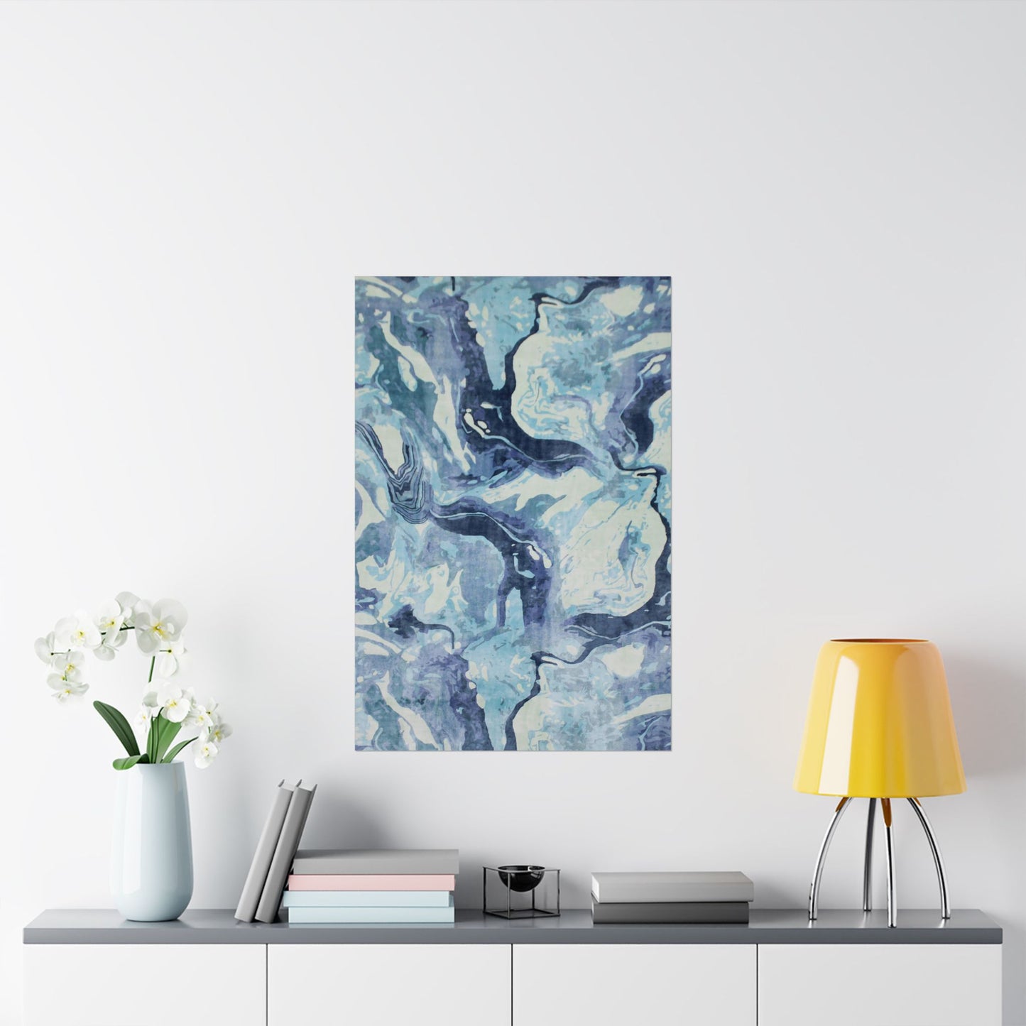 Abstract blue and white painting on a wall above a shelf with decor items.