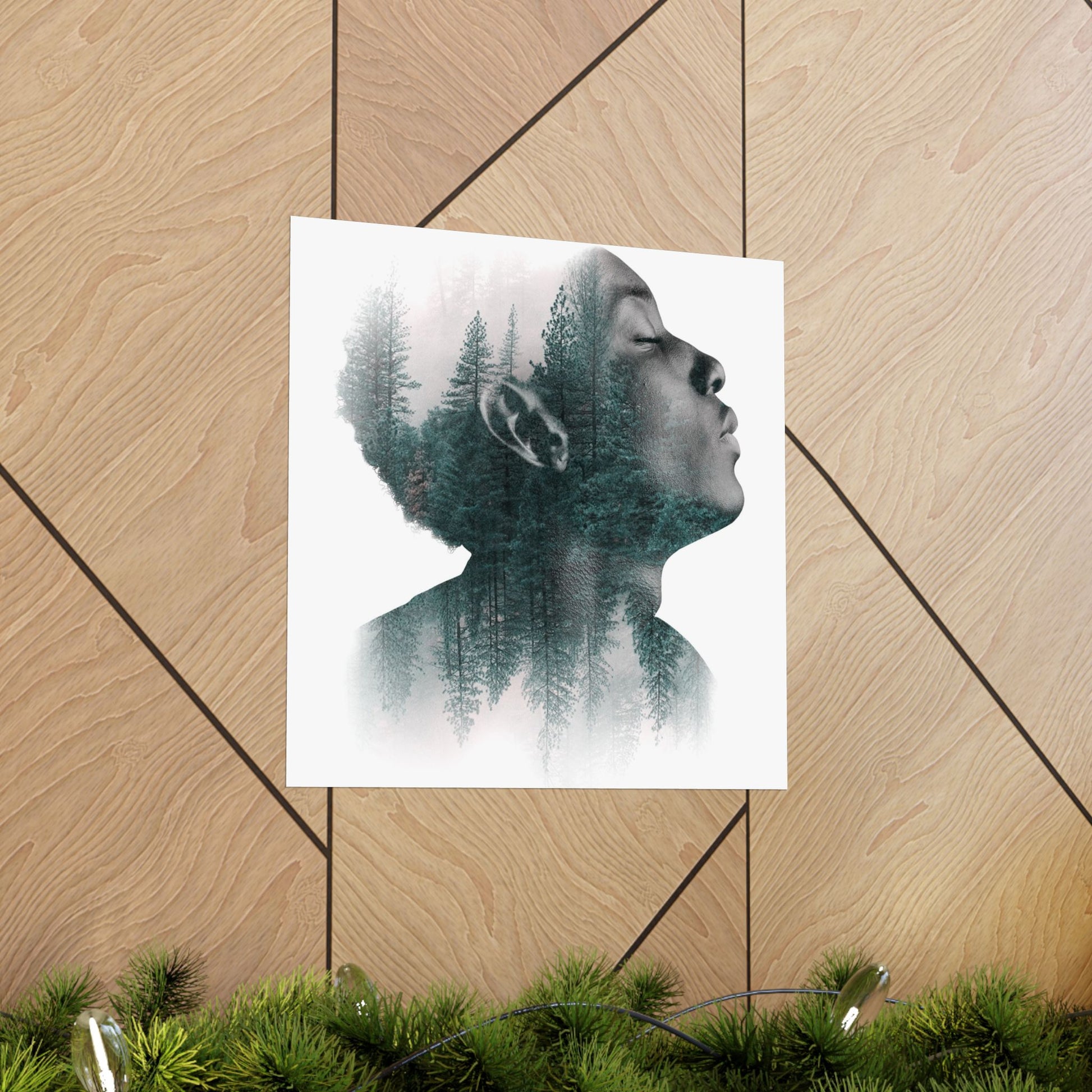 Art print of a person with trees superimposed on their hair, placed on a wooden surface.
