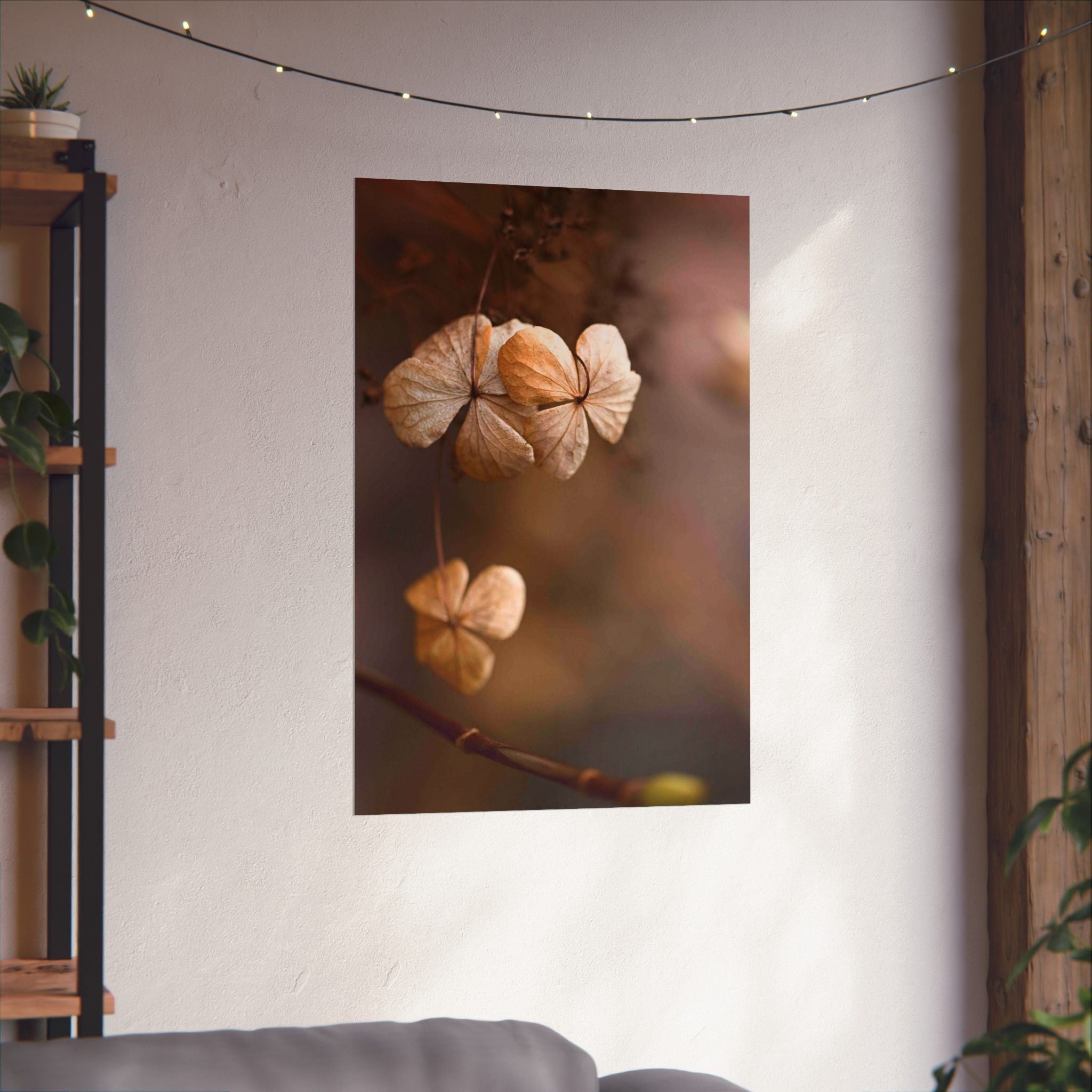 Poster of dried flowers on a wall with string lights and a plant shelf.