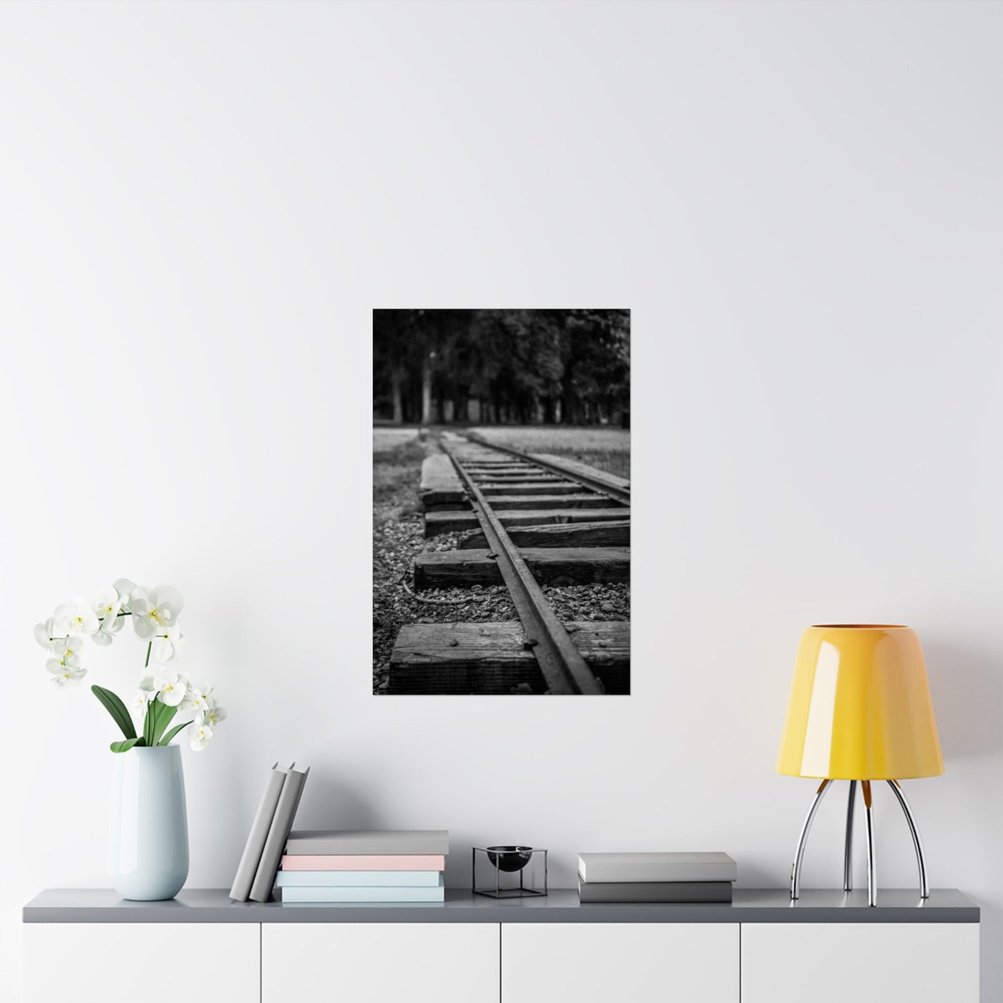 Framed black and white photograph of a railway track on a wall above a shelf with decor items.