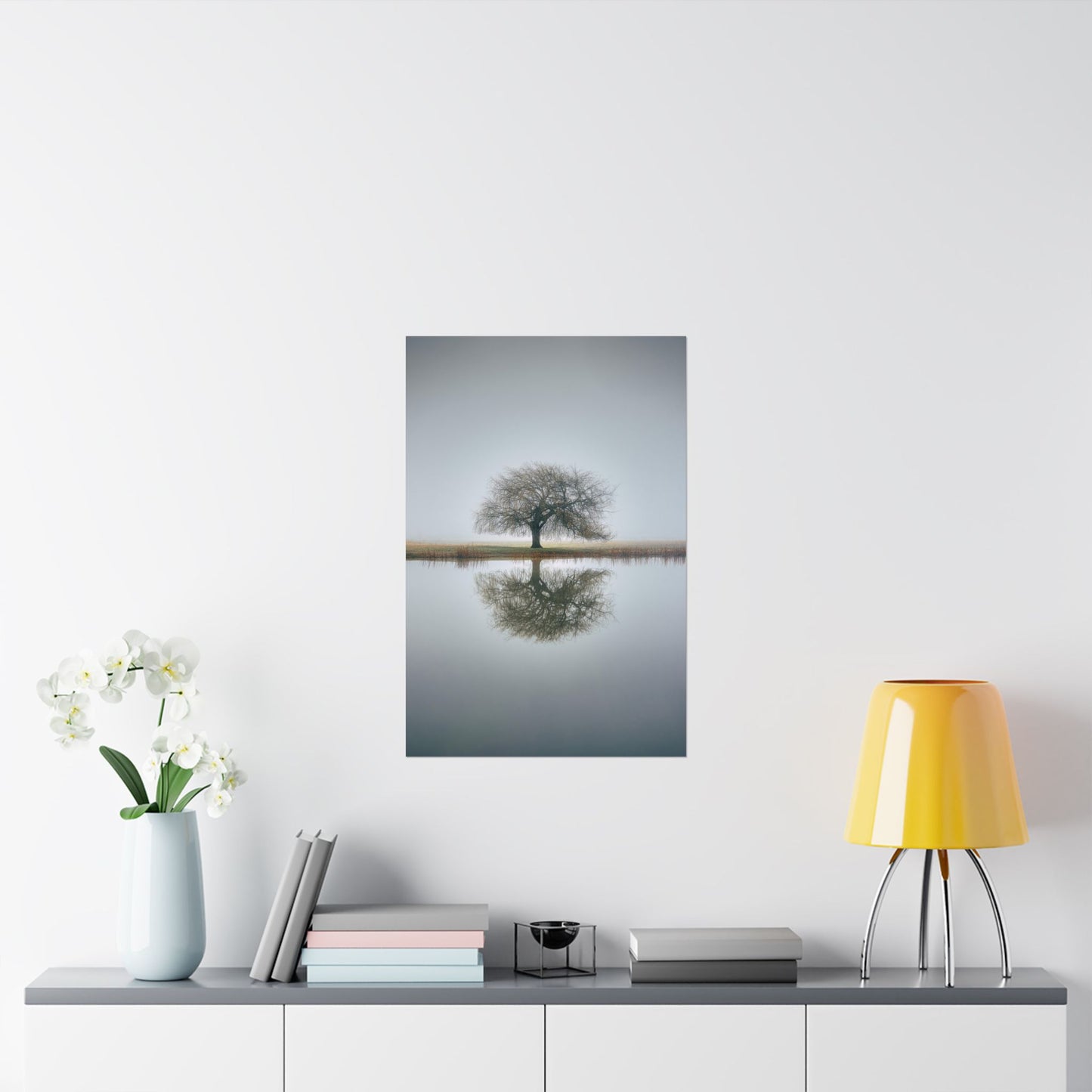 Framed artwork of a tree reflected in water on a wall above a shelf with decor items.