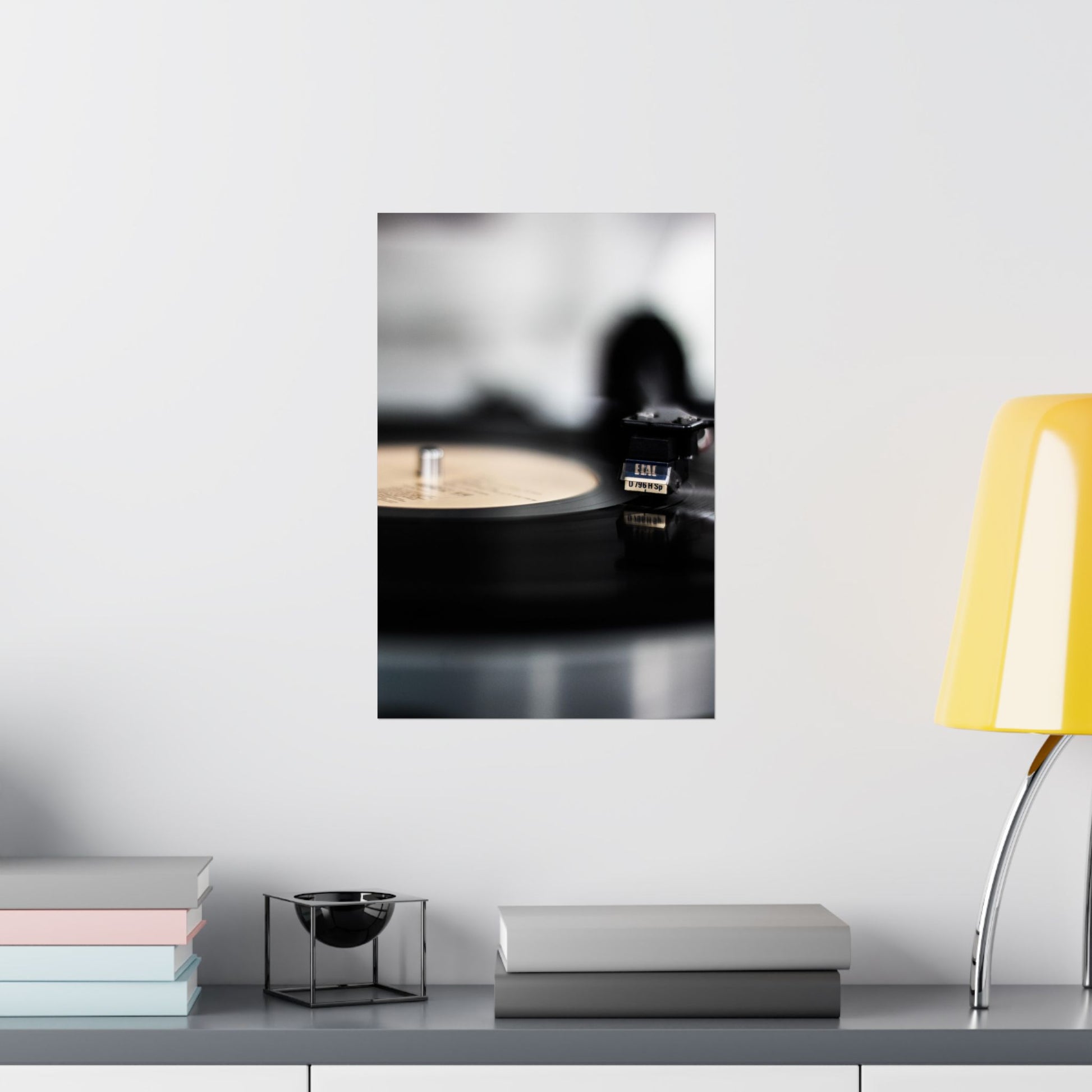 Framed artwork of a record player on a shelf with books and a lamp.