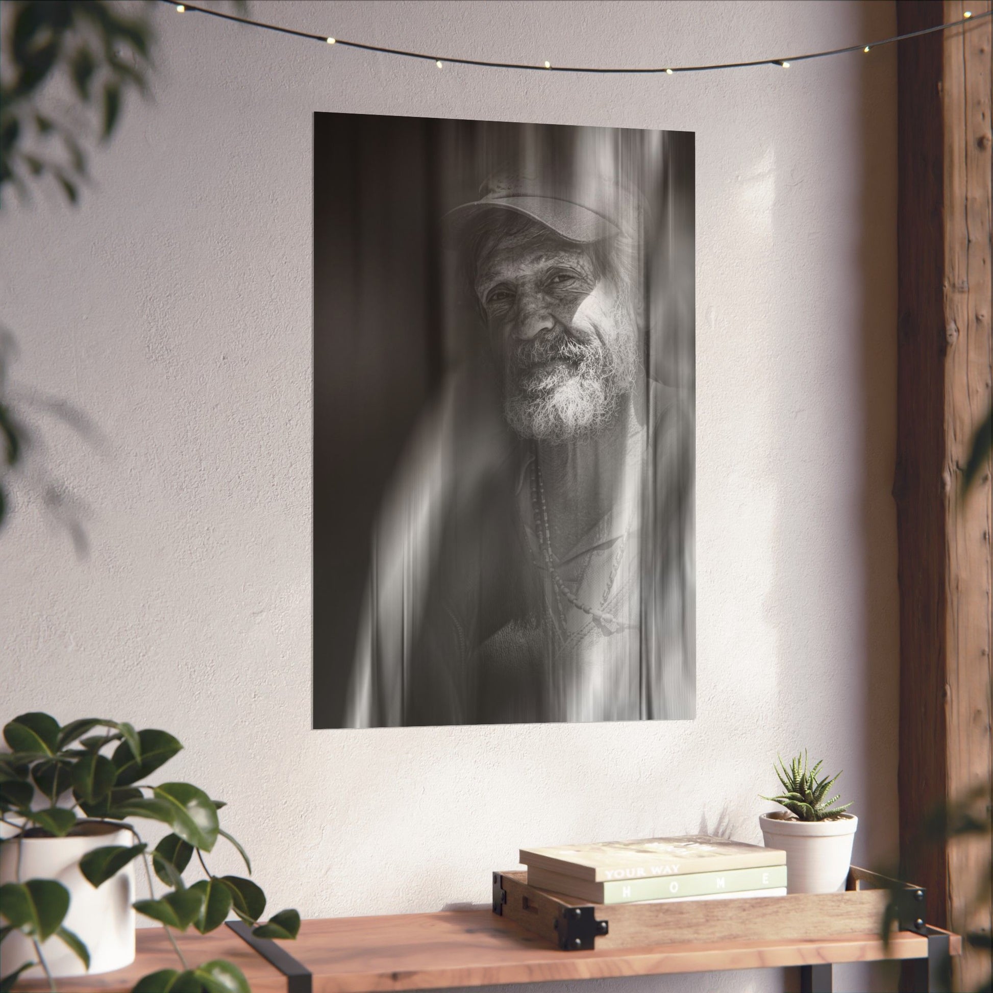 Black and white portrait of a man on a wall above a wooden shelf with books and plants.