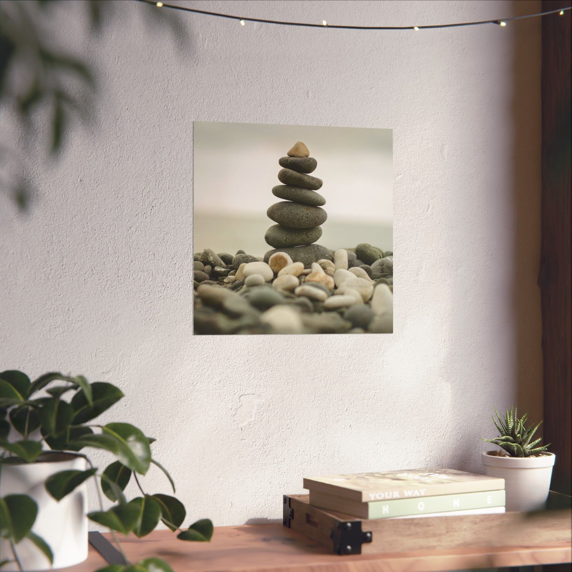 Stylized image of stacked stones on a wall with plants and books on a table below.