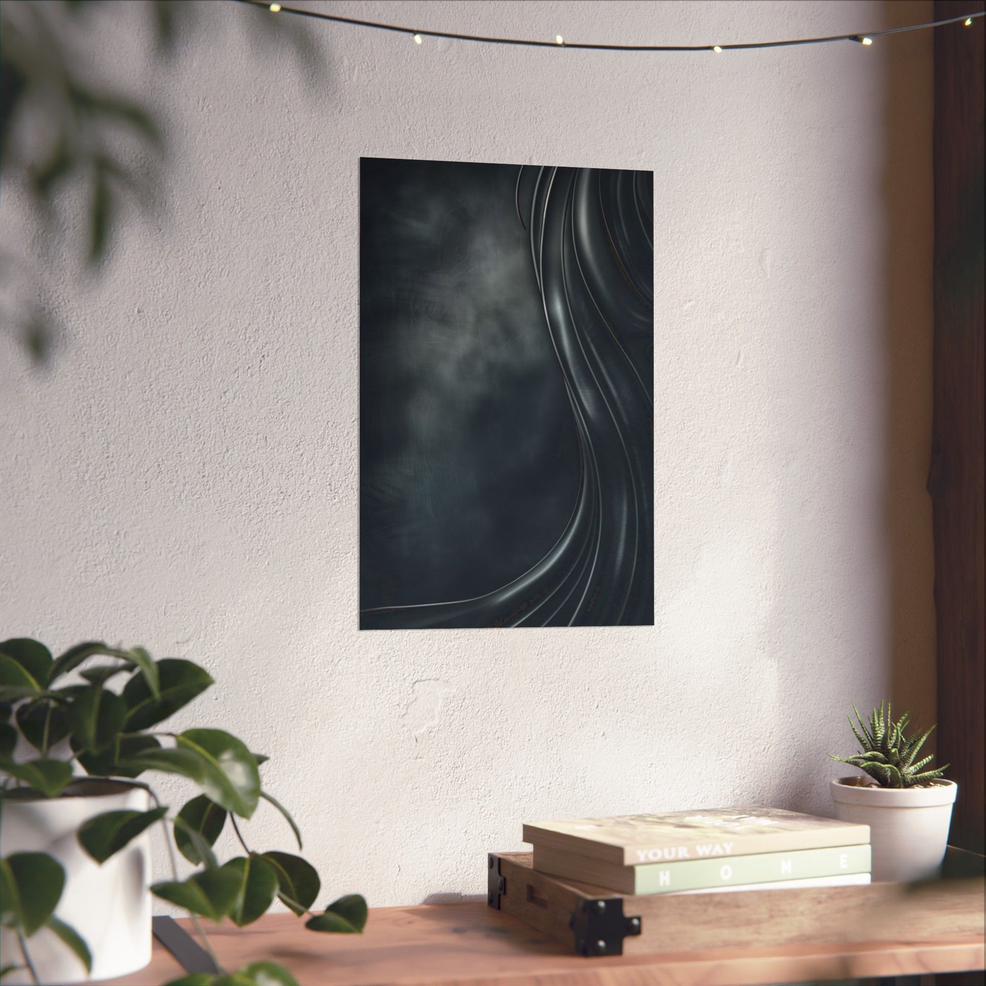Abstract black and white artwork on a wall above a wooden desk with plants and books.