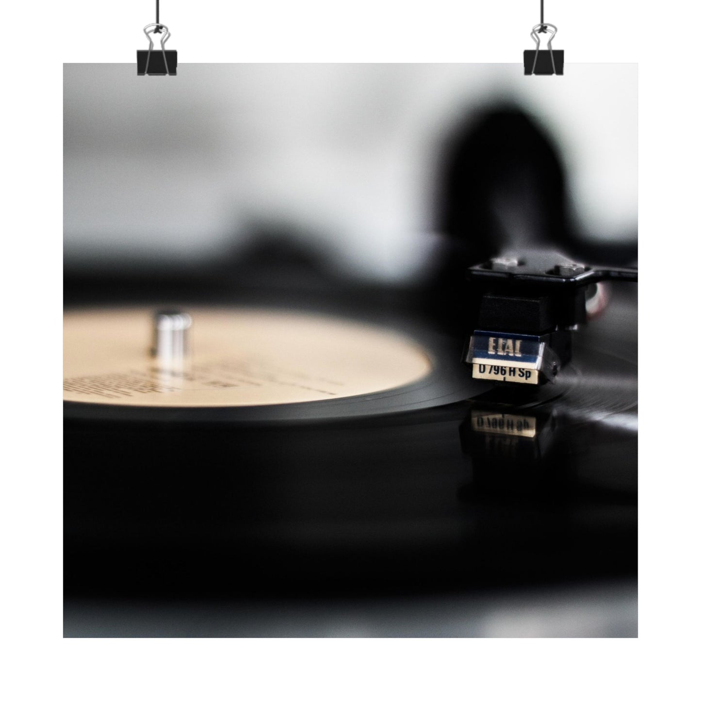 Close-up of a vinyl record and turntable on a reflective surface with a blurred background.