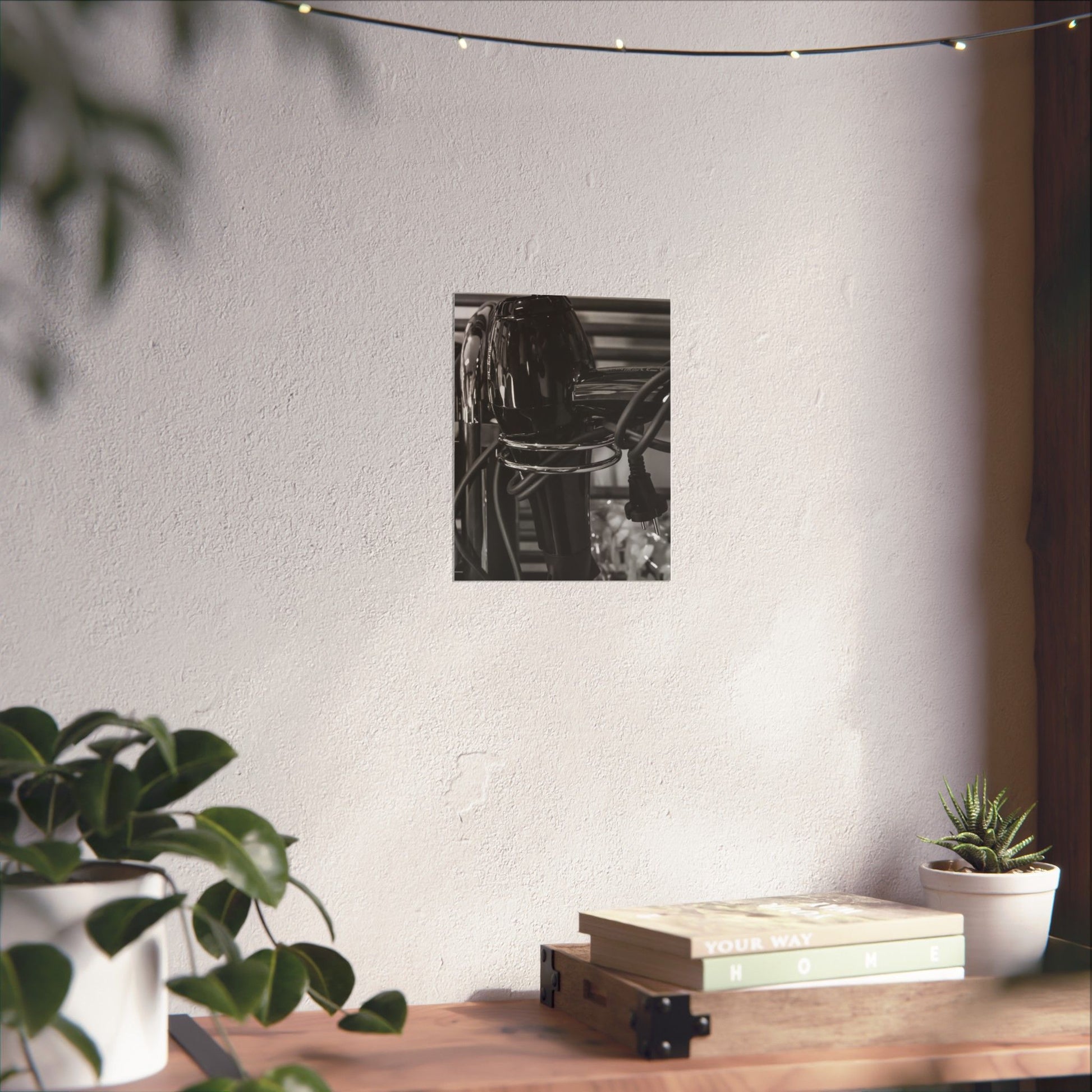 Black and white photo of a bookshelf on a white wall with plants and books on a wooden surface.