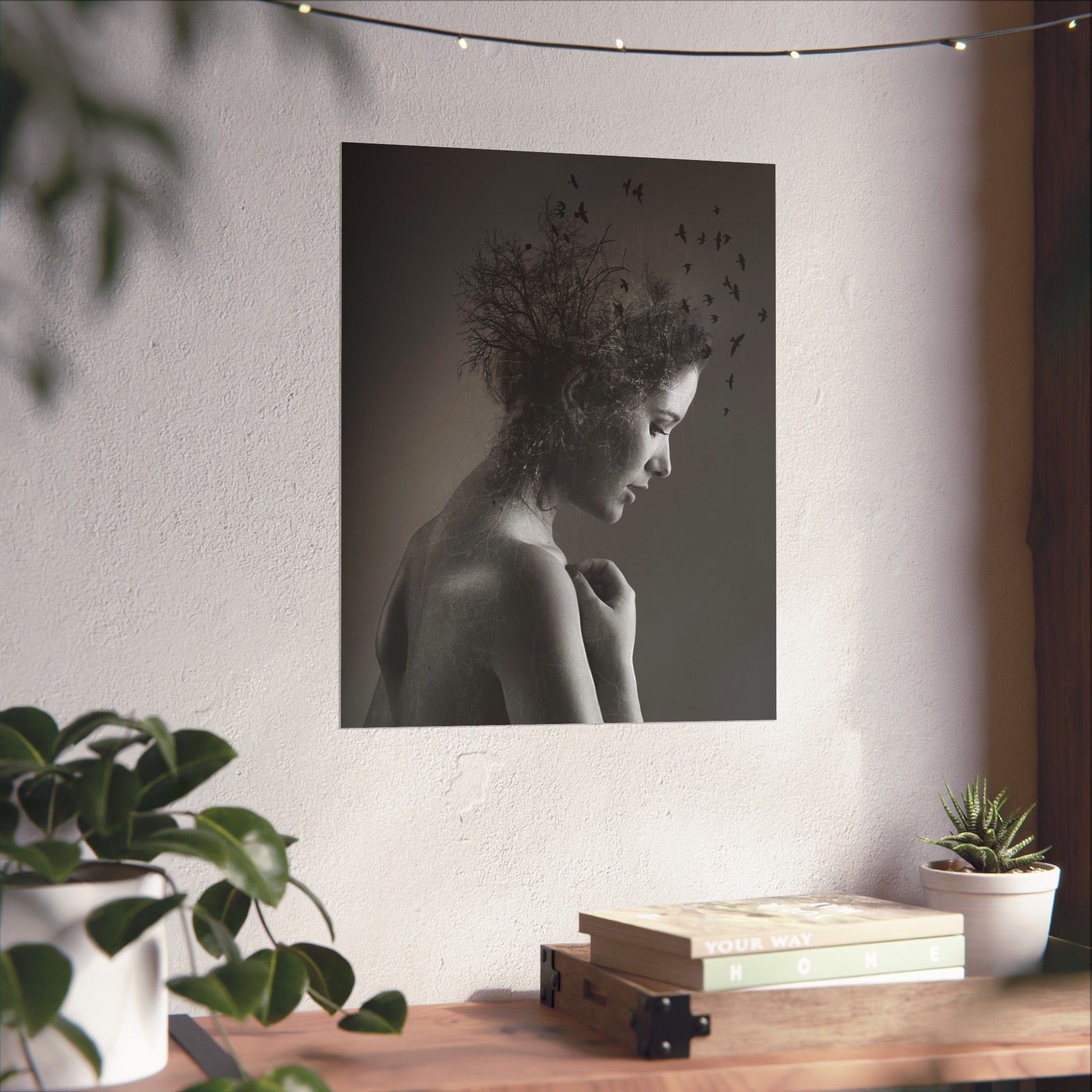 Framed black and white portrait of a woman on a wall above a wooden desk with plants.