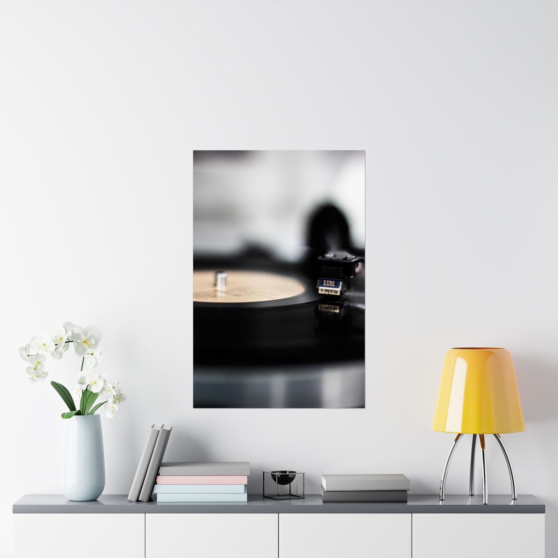 Framed artwork of a record player on a wall above a shelf with decor items.