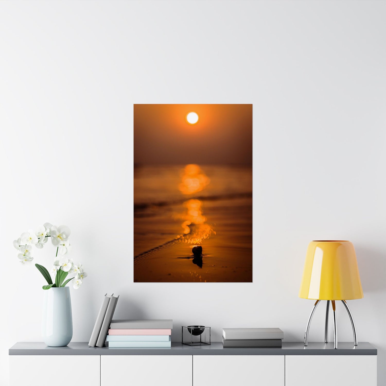 Sunset over water with a small boat on a white wall above a shelf with decor items.