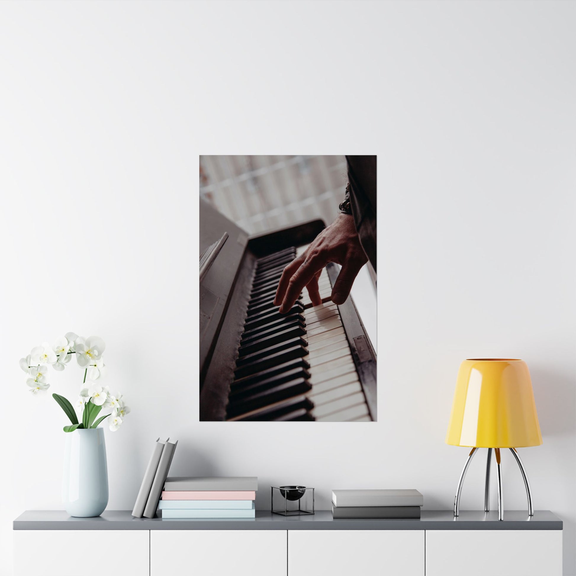 Framed picture of hands on piano keys above a shelf with decor items.