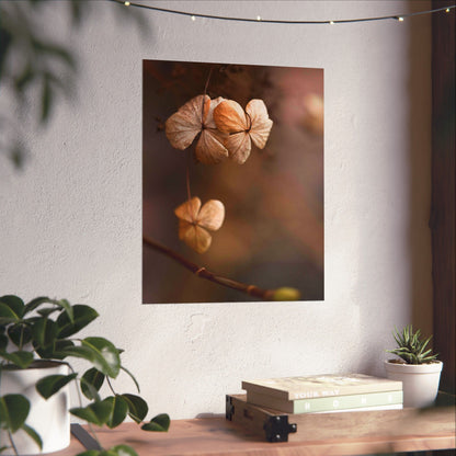 Decorative wall art of dried flowers on a white wall with plants and books on a table below.
