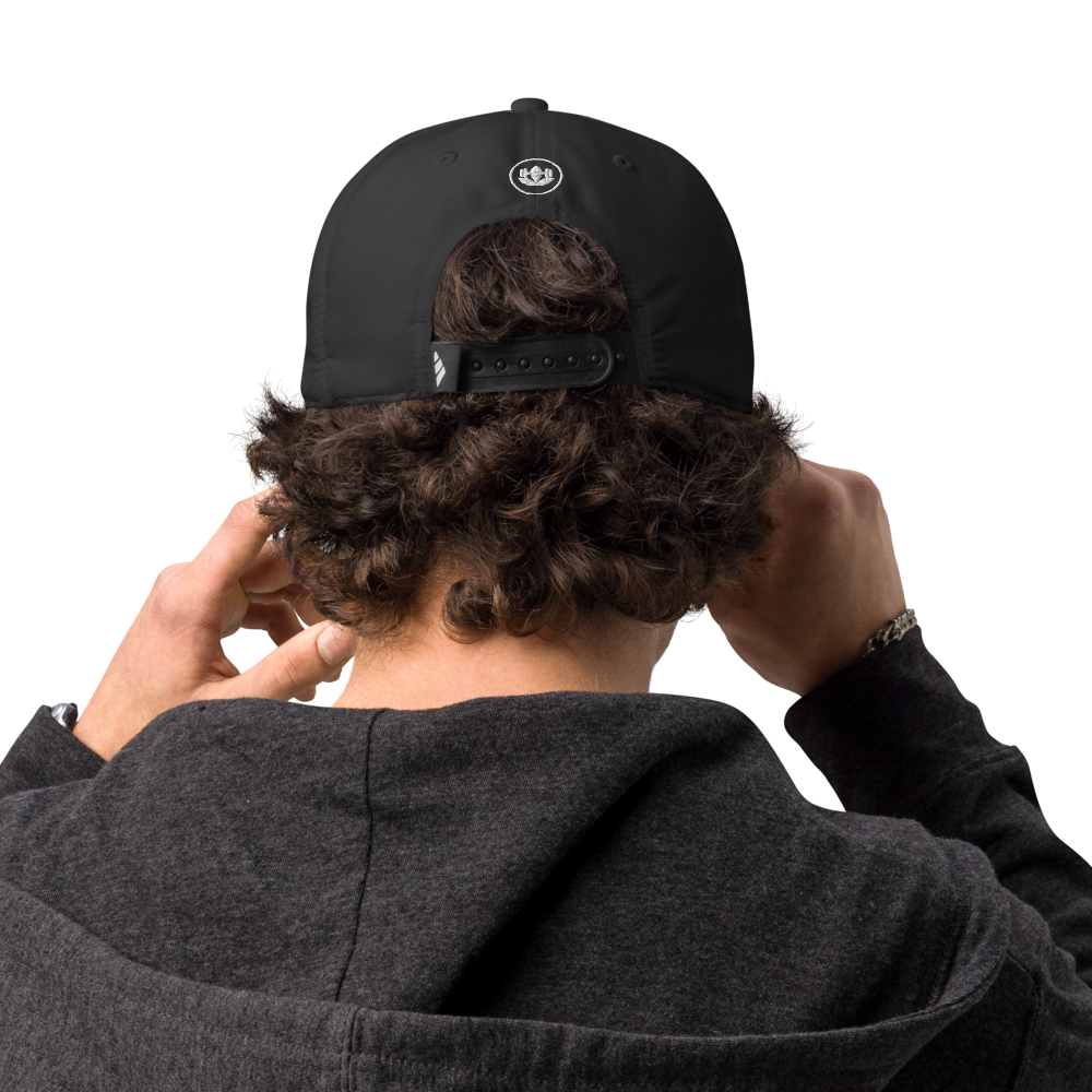 Person wearing a black cap with a logo on the back, adjusting it with both hands.