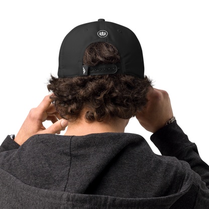 Person wearing a black cap with a logo on the back, adjusting it with both hands.