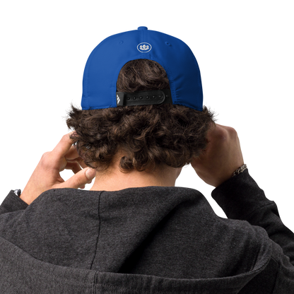 Person wearing a blue cap with a logo on the back, standing against a white background