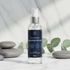 Magnesium oil spray bottle with a blue label on a white surface with stones and eucalyptus leaves.