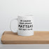 A white ceramic mug with text printed on it, placed on a wooden surface. The text reads, &
