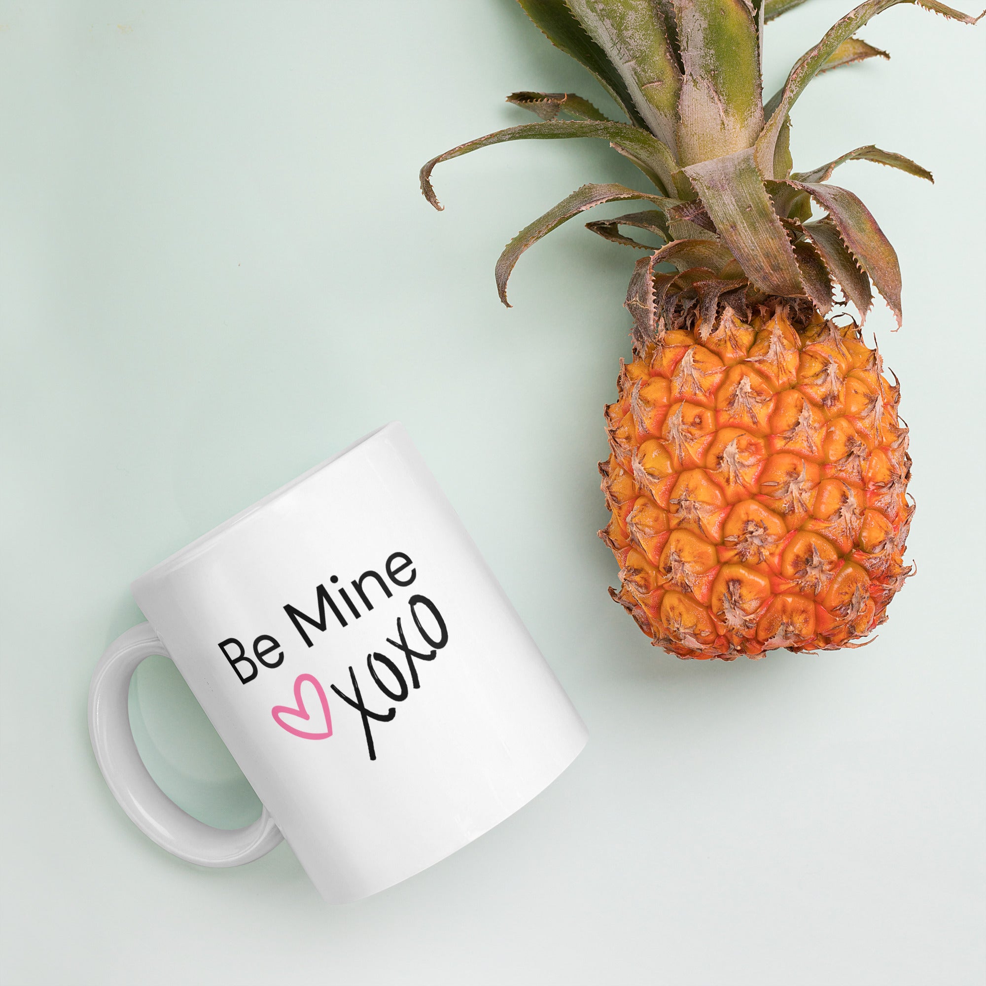 Product mockupWhite ceramic coffee mug with black text saying Be Mine xoxo